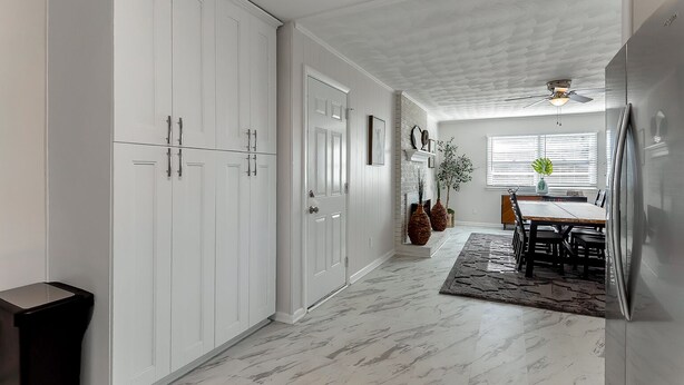 A kitchen with white cabinets, a dining area with a table and chairs, and a ceiling fan.