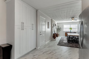 A kitchen with white cabinets, a dining area with a table and chairs, and a ceiling fan.