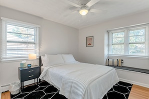 A bedroom with a bed, bedside table, lamp, and a ceiling fan.