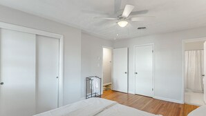 A bedroom with a bed, a ceiling fan, and a walk-in closet with two doors.