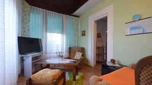 A cozy living room with a television, a dining table, and a sofa. - Apartment Potnar M with balcony (Malinska)