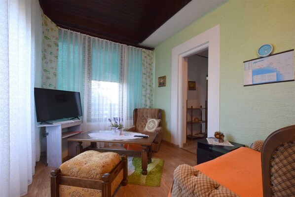 A cozy living room with a television, a dining table, and a sofa. - Apartment Potnar M with balcony (Malinska)