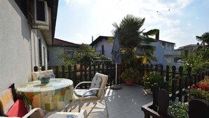 A patio with a round table and chairs, surrounded by a fence and potted plants. - Apartment Potnar M with balcony (Malinska)