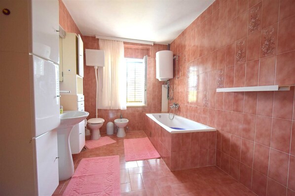 A bathroom with a toilet, sink, and bathtub. - Apartment Potnar M with balcony (Malinska)