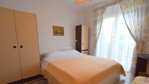 A bedroom with a bed, a wardrobe, a nightstand, and a window with curtains. - Apartment Potnar M with balcony (Malinska)