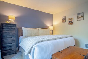 A bedroom with a bed, bedside lamps, a dresser, and wall art.
