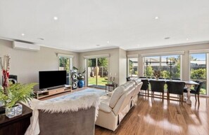 Relax in a spacious living area with a large sectional sofa, dining table, and flat-screen TV.