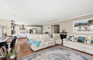 Relax in a spacious living area with a sofa set and dining table, surrounded by a modern aesthetic with clean lines and a minimalist design.