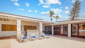 A covered outdoor area with a pool, sun loungers, and a bar.