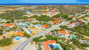 An aerial view of a coastal residential area with houses, roads, and a beach.