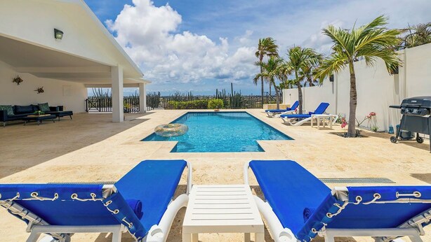 A pool area with lounge chairs, a barbecue, and palm trees. - Breathtaking Views 2BR3BA Private Pool Large Space (Noord)