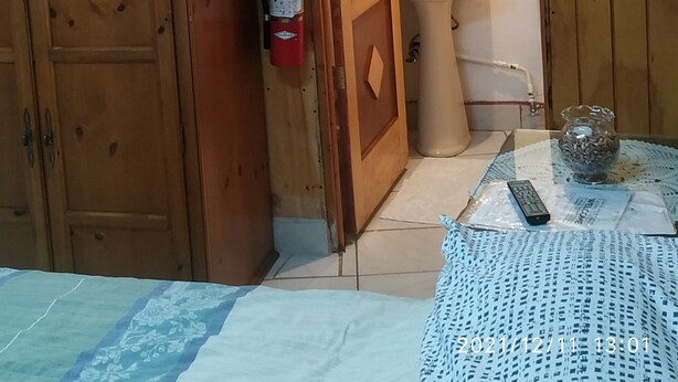 A wooden room with a door leading to a bathroom. A fire extinguisher is mounted on the wall next to the door. - Studio independiente (Ensenada)