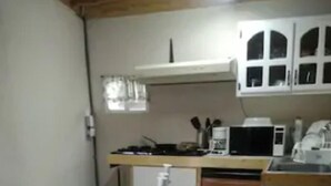 A compact kitchen with a dining table, chairs, a microwave, and a coffee maker. - Studio independiente (Ensenada)