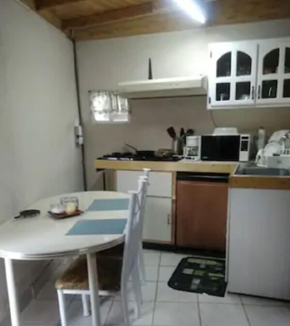 A compact kitchen with a dining table, chairs, a microwave, and a coffee maker. - Studio independiente (Ensenada)