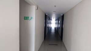 Un long couloir étroit, avec un panneau indiquant la sortie sur le mur de gauche.