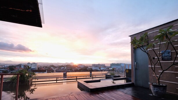 Une terrasse en bois offrant une vue sur le paysage urbain au coucher du soleil.