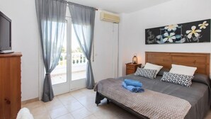 A bedroom with a bed, a nightstand, a TV, and a window with curtains. - Villa Zefir by Interhome (Miami Platja)