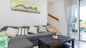 A modern living room with a grey sectional sofa, a black coffee table, and a staircase leading to an outdoor area. - Villa Zefir by Interhome (Miami Platja)