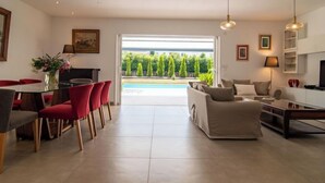 A modern living room with a sofa, a dining area with red chairs, and a kitchen area. - Villa D'Allongue by Interhome (Callian)