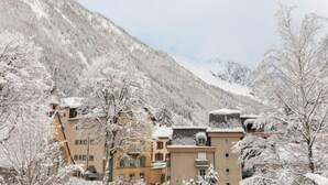 Ein Hotel mit mehreren Etagen, umgeben von schneebedeckten Bäumen und Bergen.
