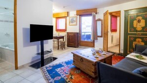 Ein kompakter Wohnraum mit Fernseher, einer Holzkommode, einem Sofa und einem Essbereich.