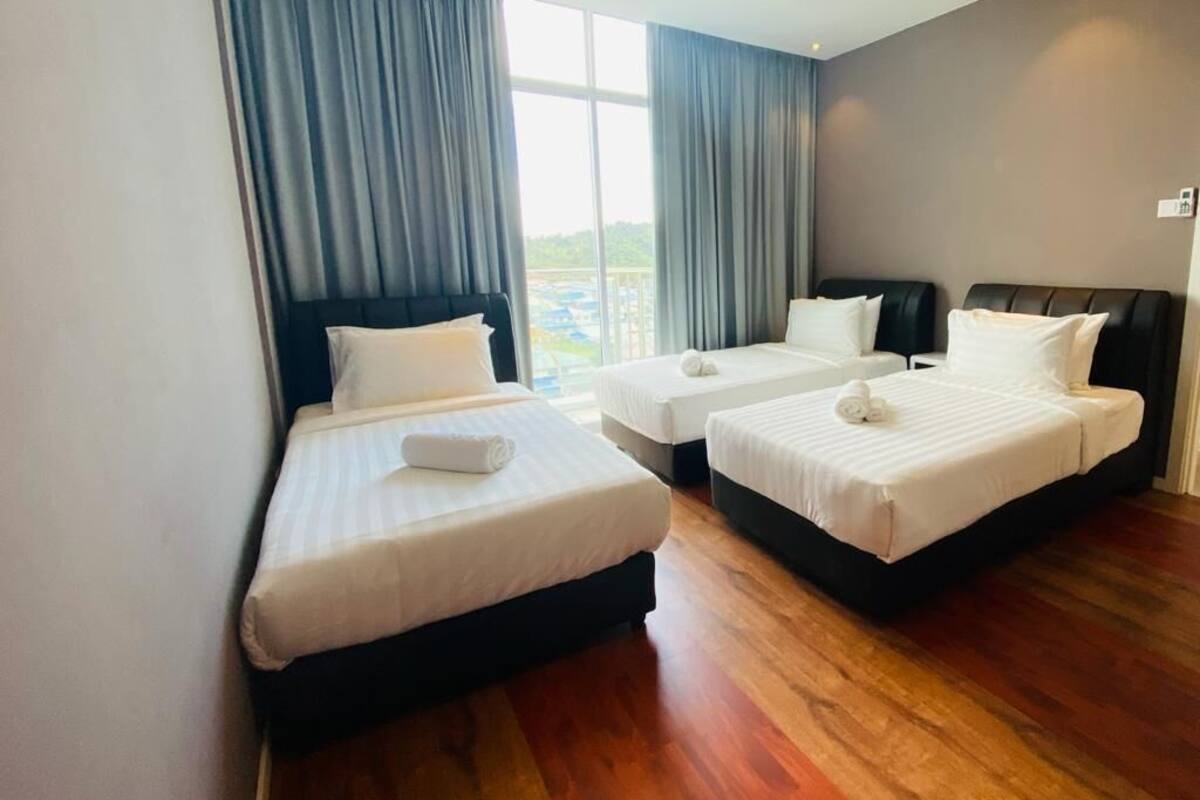 A hotel room with two beds, a large window with curtains, and a view of the outdoors.