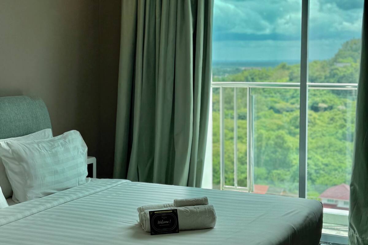 A hotel room with a bed, a pillow, a sign, and a view of the outdoors.