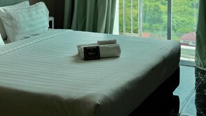 A hotel room with a large bed, a view of the outdoors, and an air conditioning unit on the wall. - Stirling Suites (Miri)