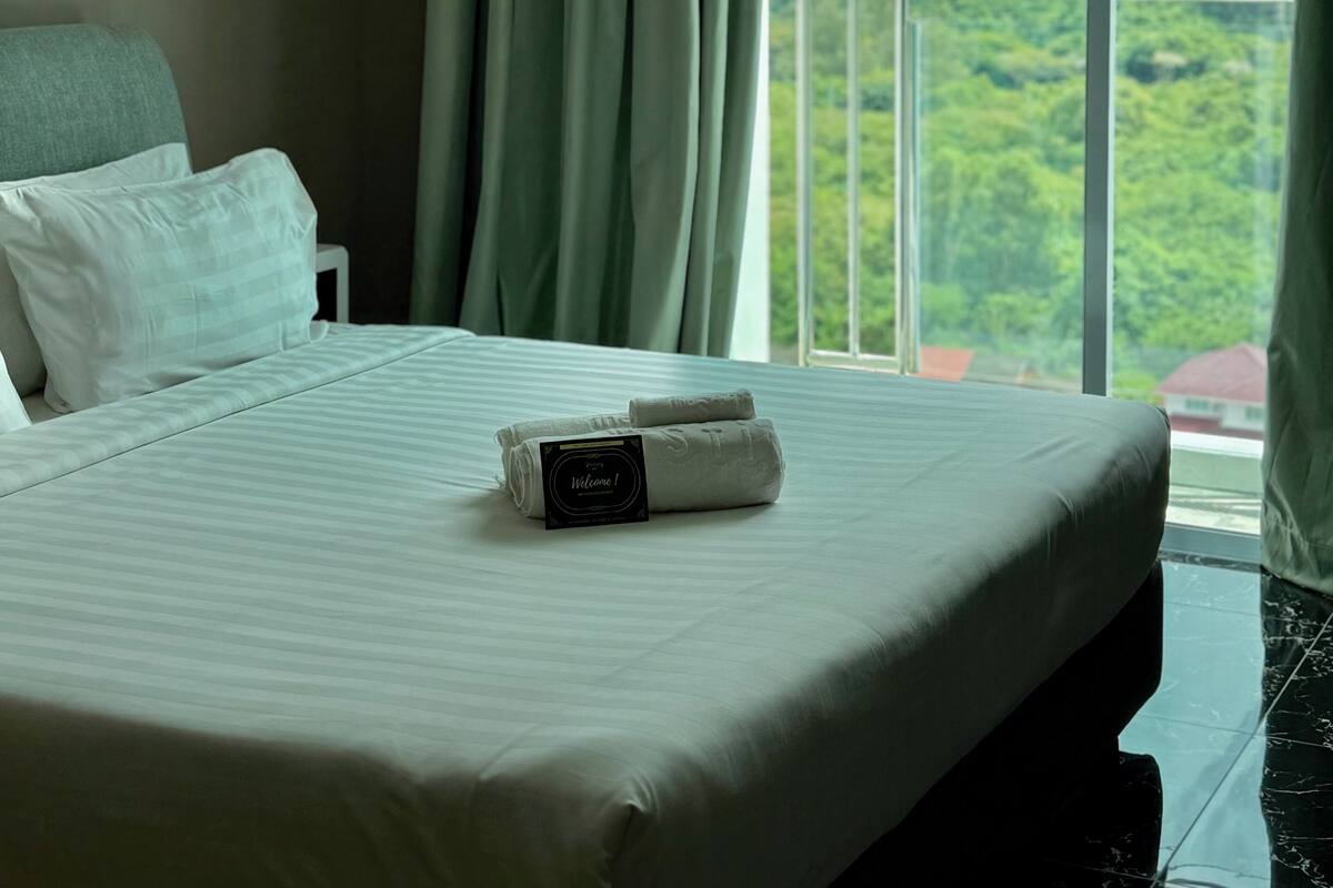 A hotel room with a large bed, a view of the outdoors, and an air conditioning unit on the wall.