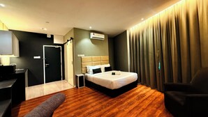 A modern hotel room with a wooden floor, a bed with white bedding, a desk with a lamp, a chair, and a large window with curtains. - Stirling Suites (Miri)