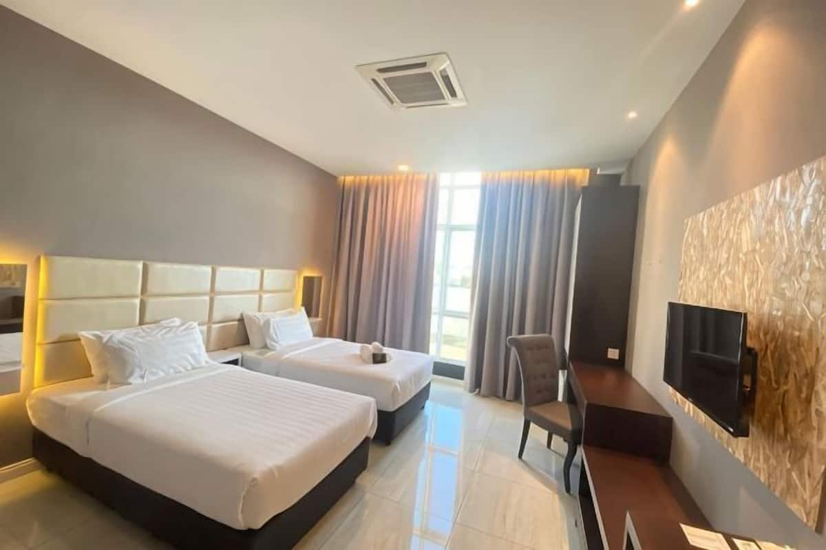 Habitación de hotel con dos camas, televisión y escritorio.