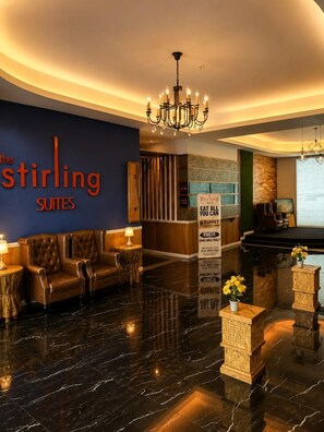 A hotel lobby with a leather sofa, a chandelier, and a sign for 'The Stirling Suites'. - Stirling Suites (Miri)