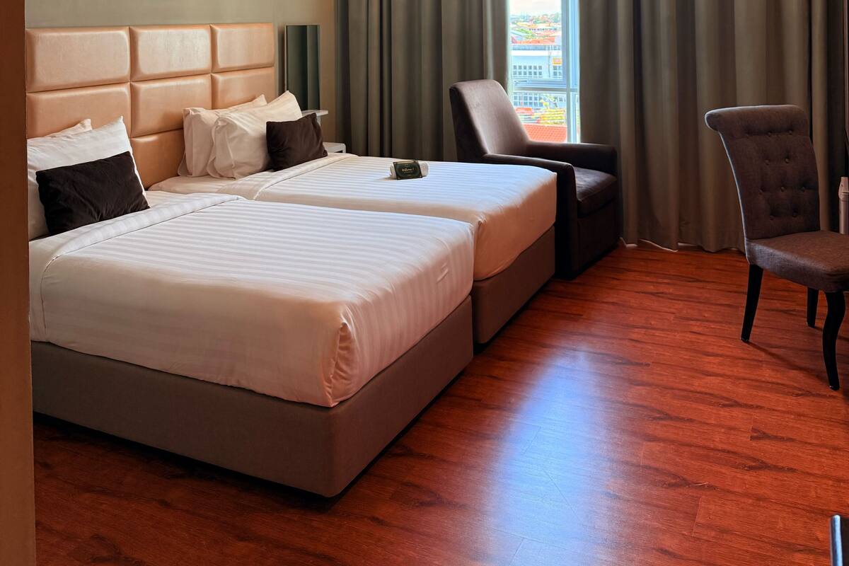 A hotel room with a large bed, a smaller bed, a desk, and a chair.