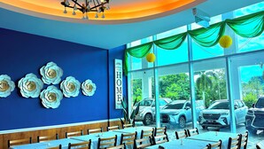 A restaurant with blue walls, a 'WELCOME TO OUR HOME' sign, and a view of parked cars outside. - Stirling Suites (Miri)