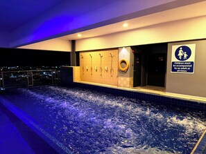 A heated indoor pool with multiple showerheads and a sign indicating children must be accompanied by an adult. - Stirling Suites (Miri)