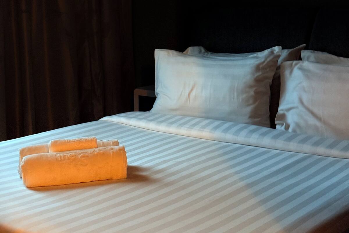 A hotel room with a bed, pillows, and a blanket.