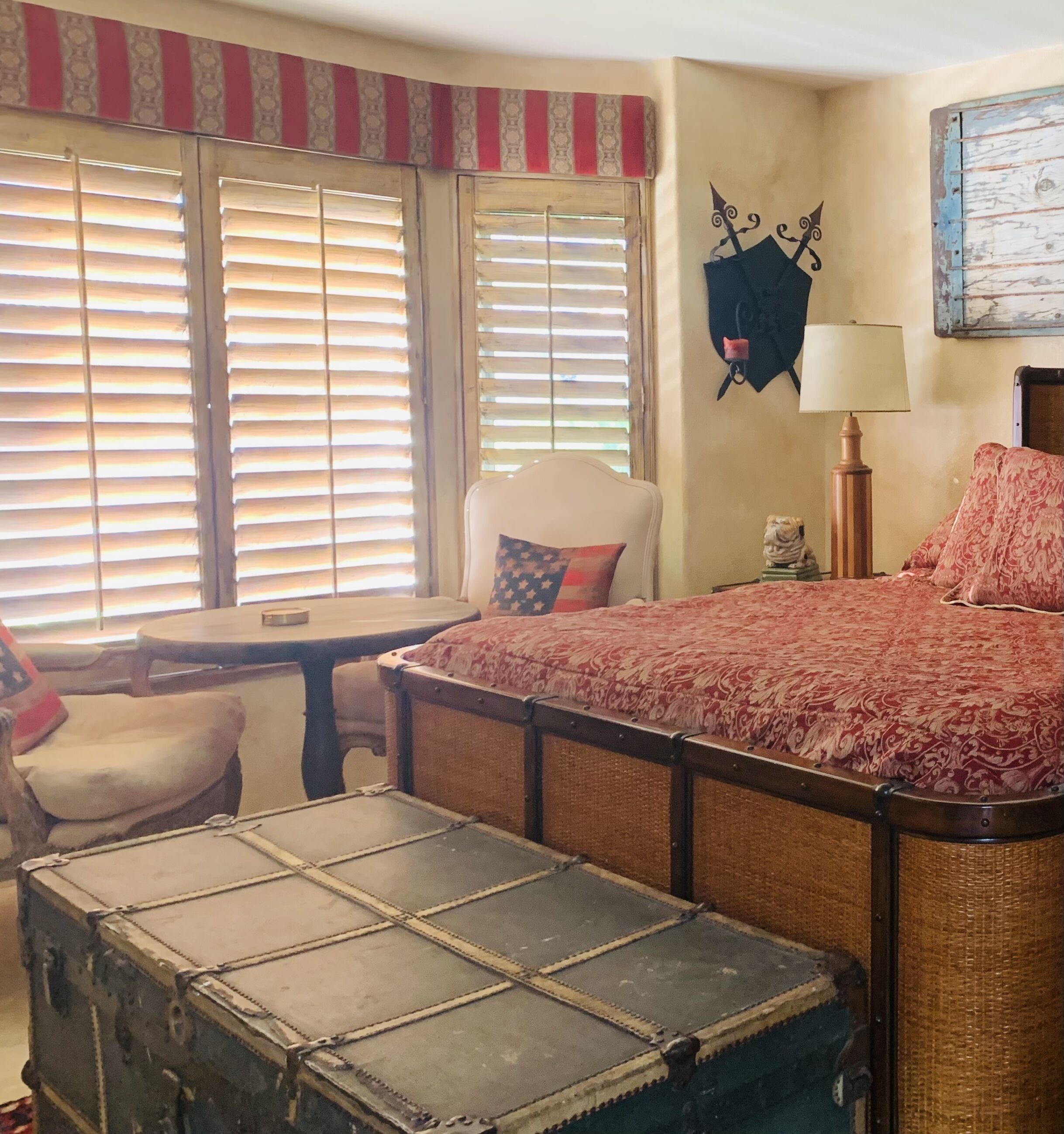 A room with a bed, a chair, a table, and a suitcase.