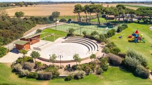 An outdoor amphitheater with tiered seating, surrounded by a fence and greenery.