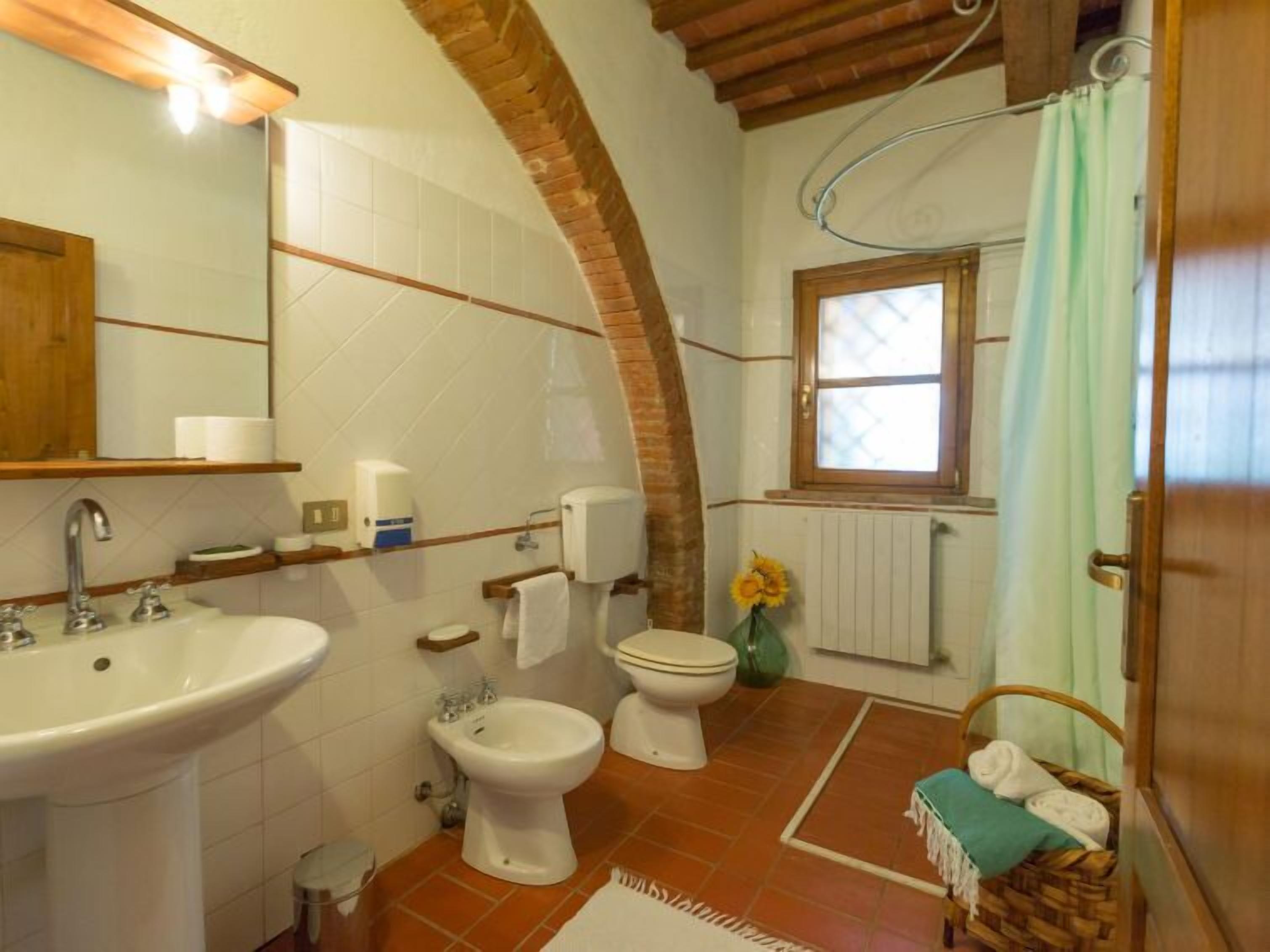 A bathroom with a sink, bidet, toilet, and a shower area.