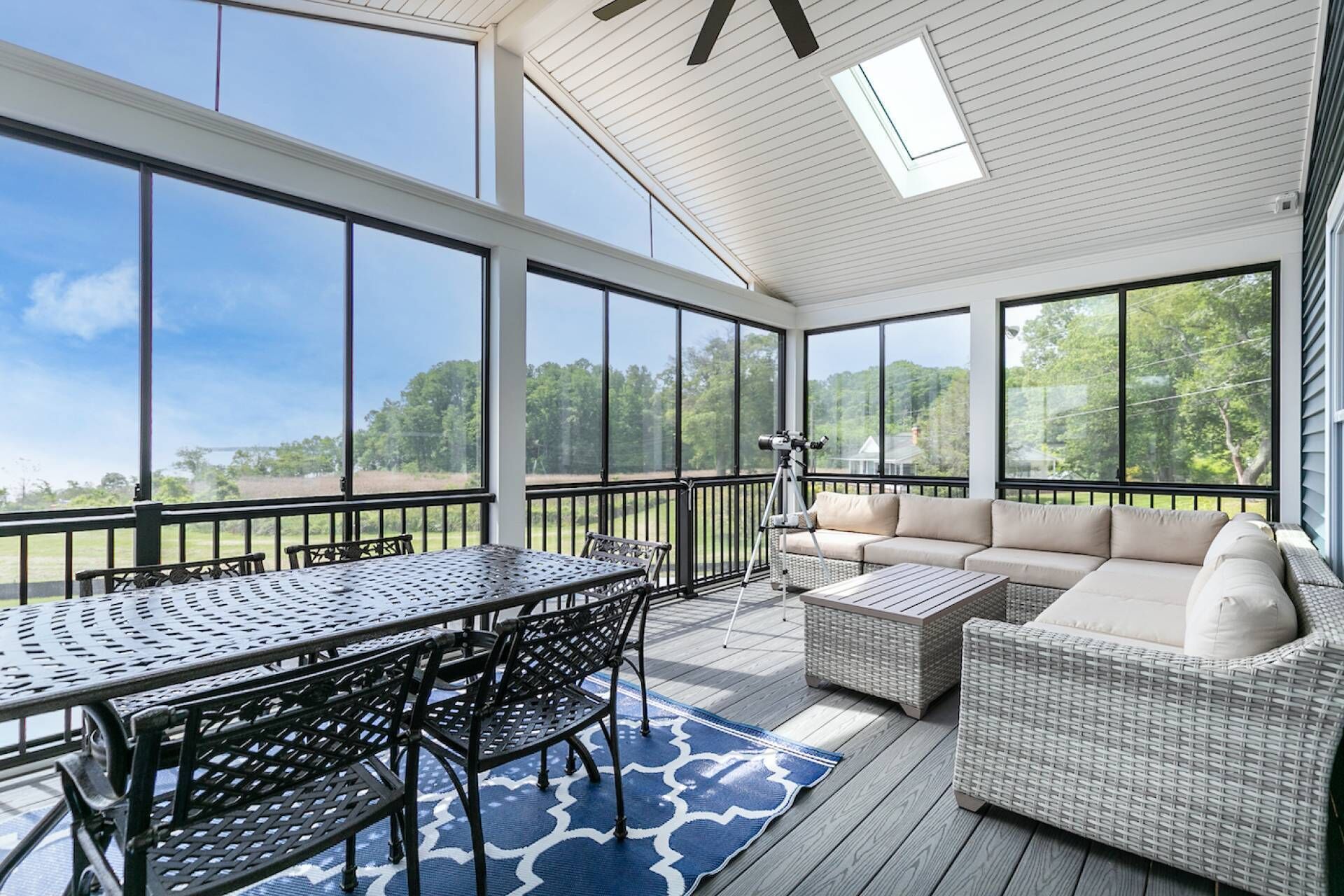 A covered patio with a dining table and chairs, a sofa, and a telescope.