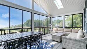A covered patio with a dining table and chairs, a sofa, and a telescope. - LUXE Private Waterfront Retreat with Pool, Hot Tub and Game Room for Family Fun (Tracys Landing)