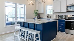 A modern kitchen with a large island, white and blue cabinets, stainless steel appliances, and pendant lighting. - LUXE Private Waterfront Retreat with Pool, Hot Tub and Game Room for Family Fun (Tracys Landing)
