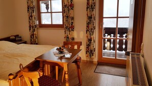 Une chambre à coucher avec un lit, une table en bois, une chaise et une fenêtre avec des rideaux.