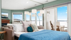 A bedroom with a bed, a view of the water, a chair, and a table. - Sauna Beach Haven 106 Direct Beach Access Near Downtown Tart Trail (Traverse City)