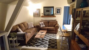 A cozy living room with two brown sofas, a coffee table, and a patterned rug. - The Hideout (Crescent City)