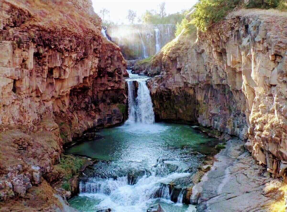 A natural waterfall in a rocky gorge with clear water.