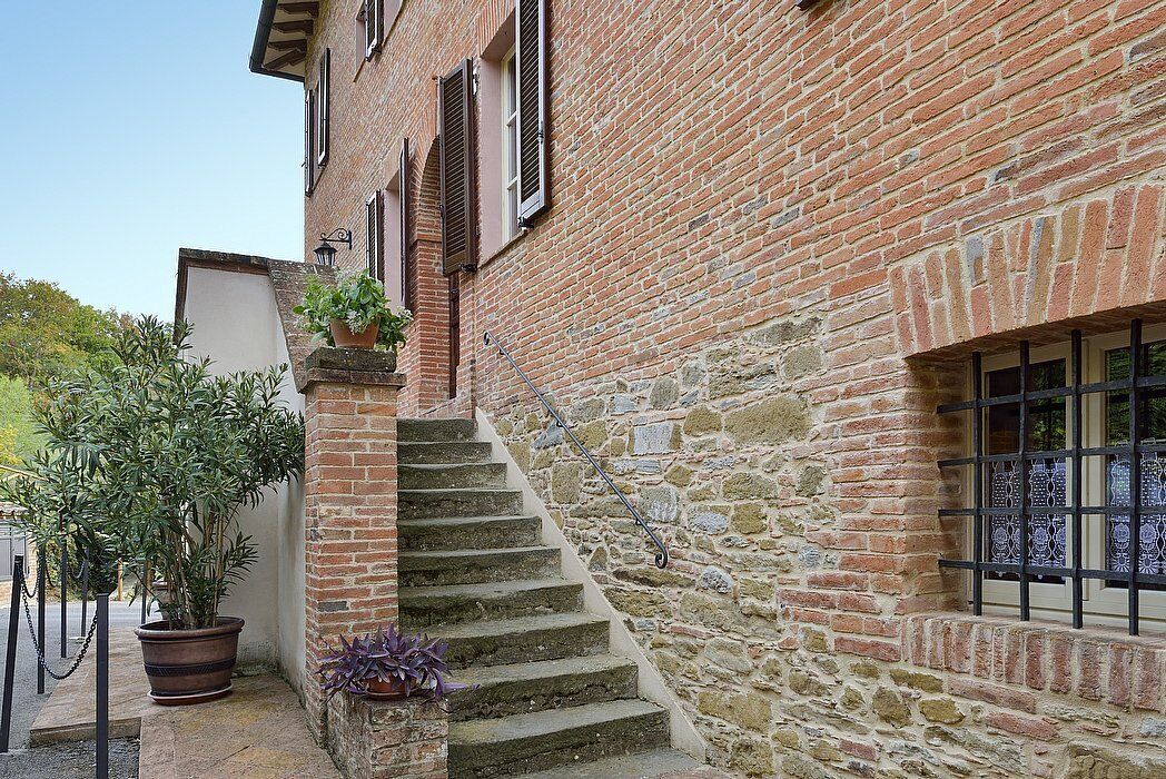 A narrow stone staircase leading to a brick building with a window featuring decorative iron bars.