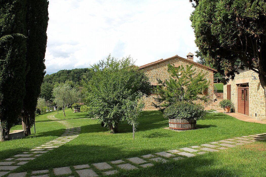A stone building with a red roof, surrounded by a well-maintained lawn and trees.