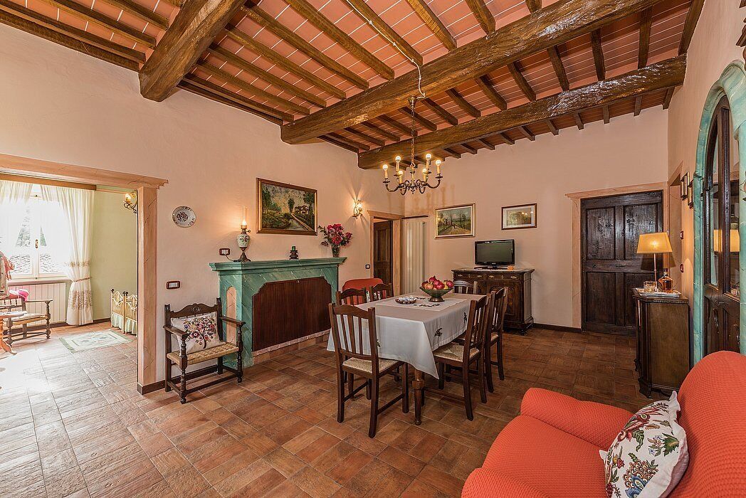 Un espace repas doté d’un plafond en bois, d’une cheminée, d’un téléviseur et d’un canapé.