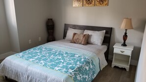 Un dormitorio con cama, mesita de noche, lámpara y decoración en la pared.